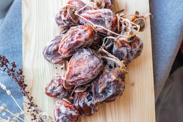 Dried sweet persimmon on wooden board with natural sugar layer. Vegan dessert.