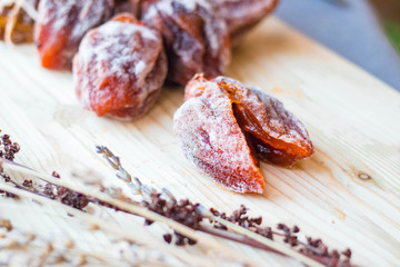 Dried sweet persimmon on wooden board with natural sugar layer. Vegan dessert.