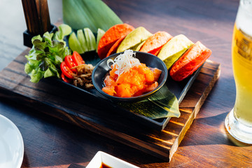 Raw Salmon Spicy Salad served with red and green crispy chips for canape and cold beer.