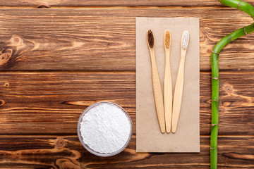 Bamboo toothbrushes, bamboo plant, dentifrice tooth powder on wooden background. Flat lay copy space. Biodegradable natural bamboo toothbrush. Eco friendly, Zero waste,Dental care Plastic free concept