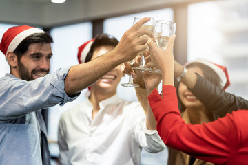 Group of various nationalities colleagues having Christmas and new year party in office. Friends clinking glass of champagne, talking together. They feeling happy with smile face enjoy Xmas activity.