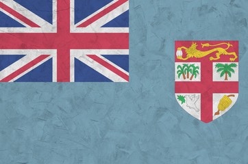 Fiji flag depicted in bright paint colors on old relief plastering wall. Textured banner on rough...