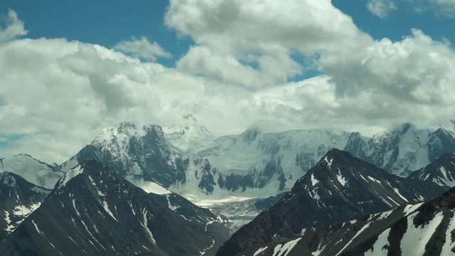 White snowy peaks of the mountain range under the clouds. The highest point of the Altai Mountains, Mount Belukha. 4k footage.