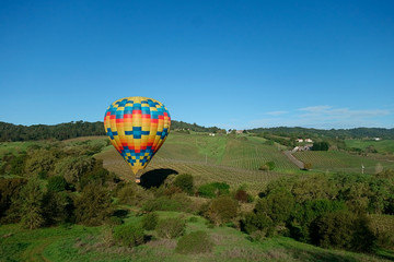 A hot air balloon dipping downward with the air drafts in Napa valley.