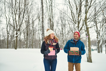Fototapeta na wymiar Smiling diverse couple holding Christmas presents while walking
