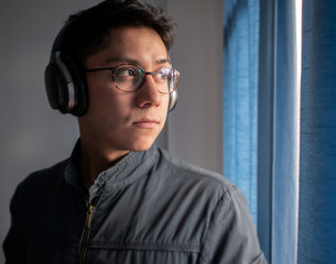 young man on glasses listening to music with headphones