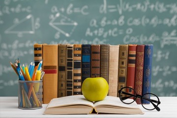 Stack of vintage books, eyeglasses and pencils, education and learning