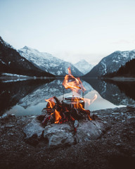 Campfire with teapot in front of the mountains at the lake