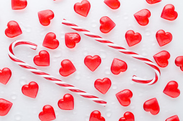 white background with red hearts pattern and candy canes, flat lay