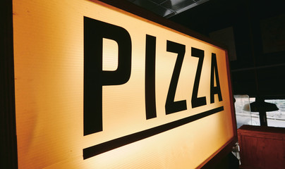 A trendy iconic cinematic typist font new york pizza sign inside a retro vintage hipster pizza diner in a city. Pop up eatery style pizza counter.