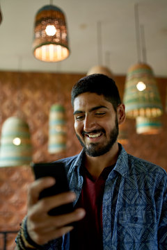 Handsome millennial man with beard using smartphone for video ca