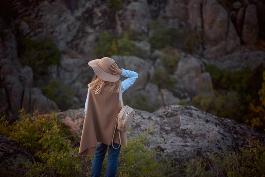 Beautiful fashionable girl blogger in a hat and vest travels the world, photo on the background of the canyon, the concept of travel and outdoor activities