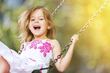 Little child blond girl having fun on a swing