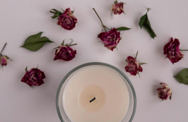 white candle with husked roses on a white background