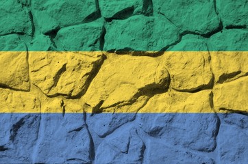 Gabon flag depicted in paint colors on old stone wall closeup. Textured banner on rock wall...