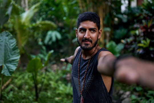 Young healthy attractive male practicing asana yoga in tropical