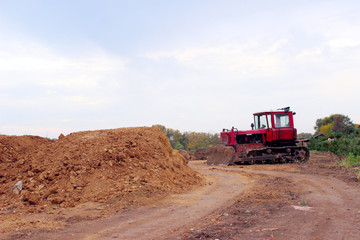 An old red bulldozer outdoors. An excavator stands among gravel, stones and earth in a quarry.