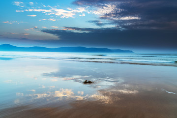 Fototapeta na wymiar Hazy and Cloudy Sunrise Beach Reflections