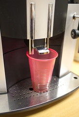 Red plastic cup in a coffee machine