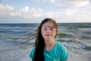 Portrait of down syndrome girl smiling on background of the sea