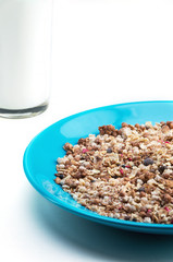 Muesli flakes in blue plate and glass of milk on white background selective focus