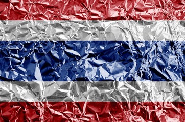 Thailand flag depicted in paint colors on shiny crumpled aluminium foil closeup. Textured banner on...