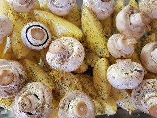 Slices of potatoes and whole champignons for baked in the oven, cooking process.