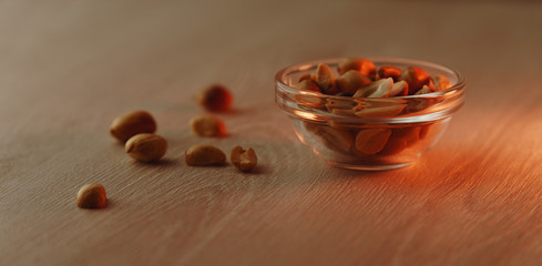Healthy snack - very small cup of peanuts placed on a light wooden surface