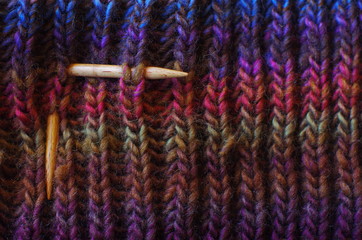 Multi-colored knitwork. knitting needles rib stitch pattern. knitting scarf in ribbed stitches