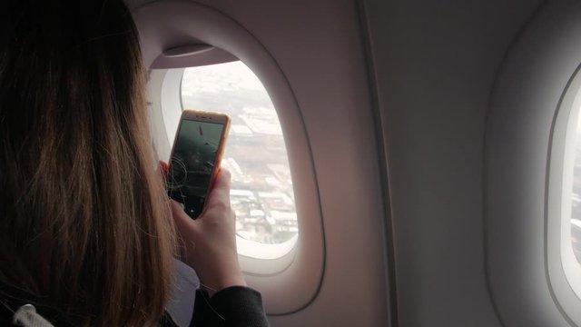 Girl takes picture from plane phone young happy smiling woman with smartphone sitting on airplane