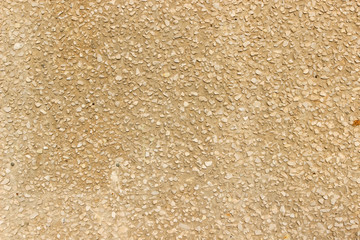 Texture of a wall made of crushed stone plastered with cement painted in yellow