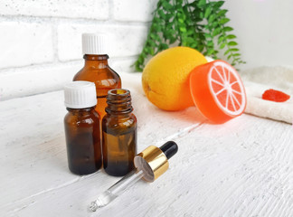 Aroma essential oil bottles with orange citrus soap on white wooden background. Spa arometherapy and alternative medicine concept.