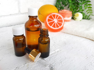 Aroma essential oil bottles over orange citrus  on white wooden background. Spa arometherapy and alternative medicine concept.