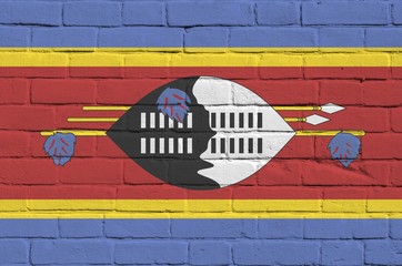 Swaziland flag depicted in paint colors on old brick wall. Textured banner on big brick wall...
