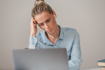 Portrait of young girl student tired of studying sitting at table with computer books and...