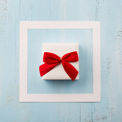 Handmade wrapped gift box, red bow on wooden blue background