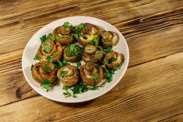 Baked mushrooms in plate on wooden table