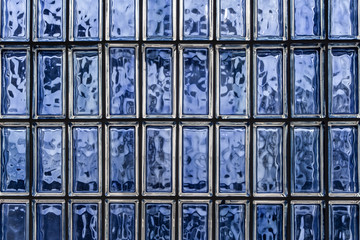 A beautiful horizontal texture of part of a white glass transparent square brick wall in blue hue