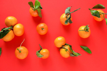 Orange tangerine with leaves on an red background