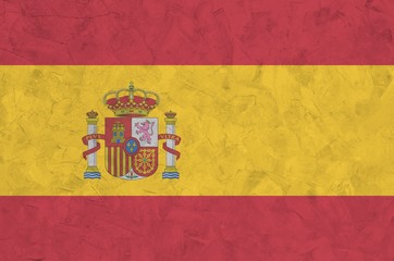 Spain flag depicted in bright paint colors on old relief plastering wall. Textured banner on rough...