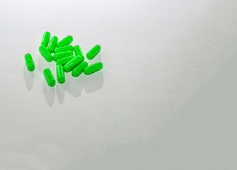 Scattered green pills on white paper. Layout for special offers, advertising, web background. The concept of medicine, pharmacy, healthcare. Empty space for text, logo. Close-up, isolate of drugs