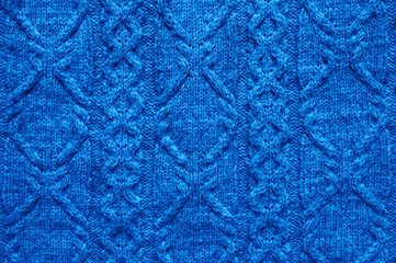 Seamless knitwear fabric texture with pigtails. Knitting texture of sweater or scarf or plaid. Knitted background. Close up, top view. Classic blue color 2020