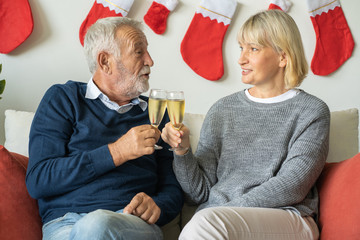 Senior couple holding glass of champagne to celebrate together at home for Christmas festival day, Retirement lifestyle concept