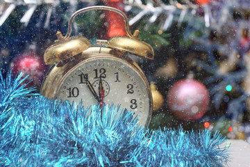 Vintage clock on a background of colored garlands and Christmas tree branch. Concept - New Year