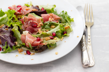 salad prosciutto with pomegranate on white plate