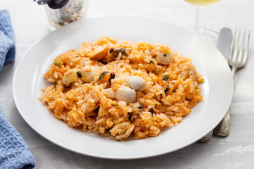 rice with seafood on white plate on ceramic background