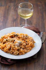 rice with seafood on white plate on brown wooden background