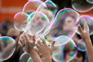 Hands of children trying to reach soap bubbles