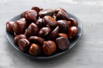 fresh chestnuts on dish on ceramic background