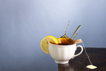 a mug of lemon tea with a falling slice of sugar and a splash from its fall